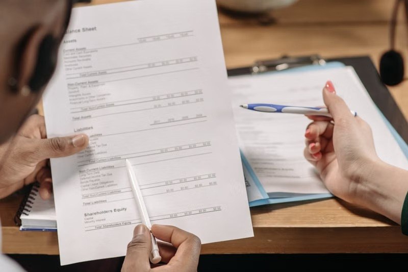 Advisor and client reviewing a balance sheet with pens